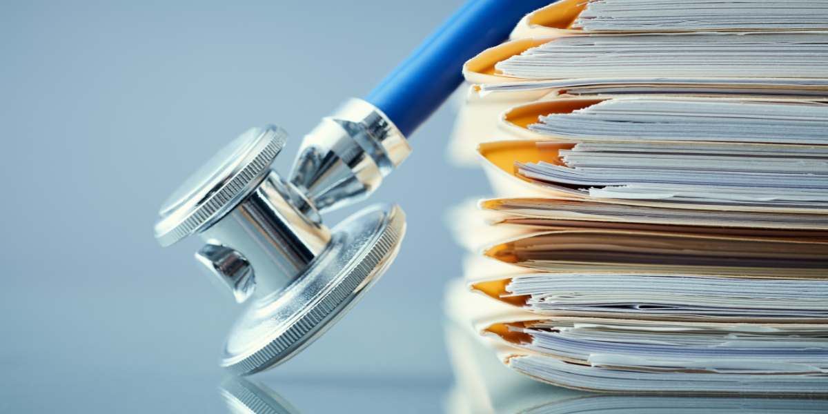 stack of medical documents in file folders with a stethoscope resting over it.