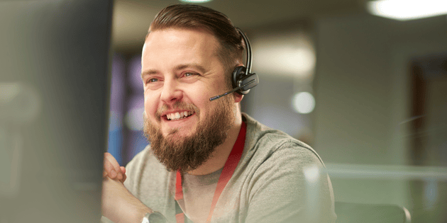 Smiling managed IT expert offering support to customer over a headset.