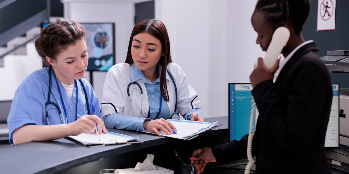 Doctor and nurse overlooking medical documents that they want to send through HIPAA compliant fax at medical office desk.