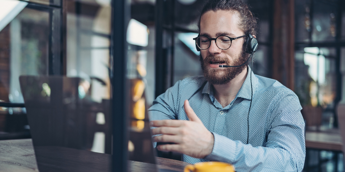 Man looking at computer while speaking to someone over headset as he proved IT support for small businesses