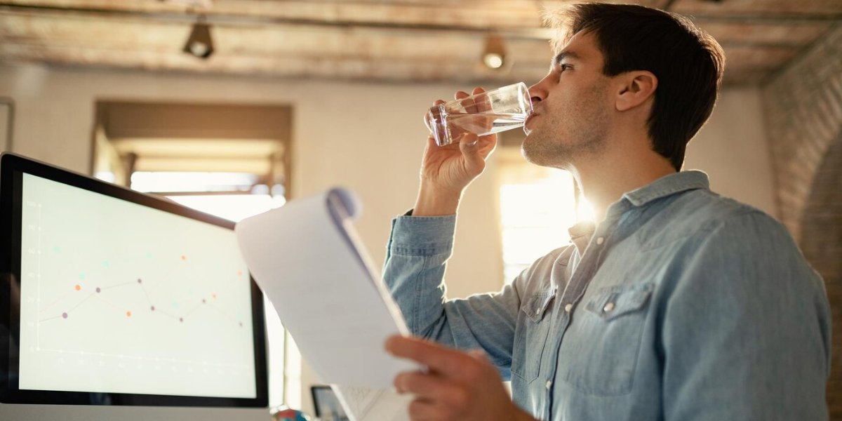 Office worker drinking glass of water that is clean because his office manager understands the importance of water filtration.
