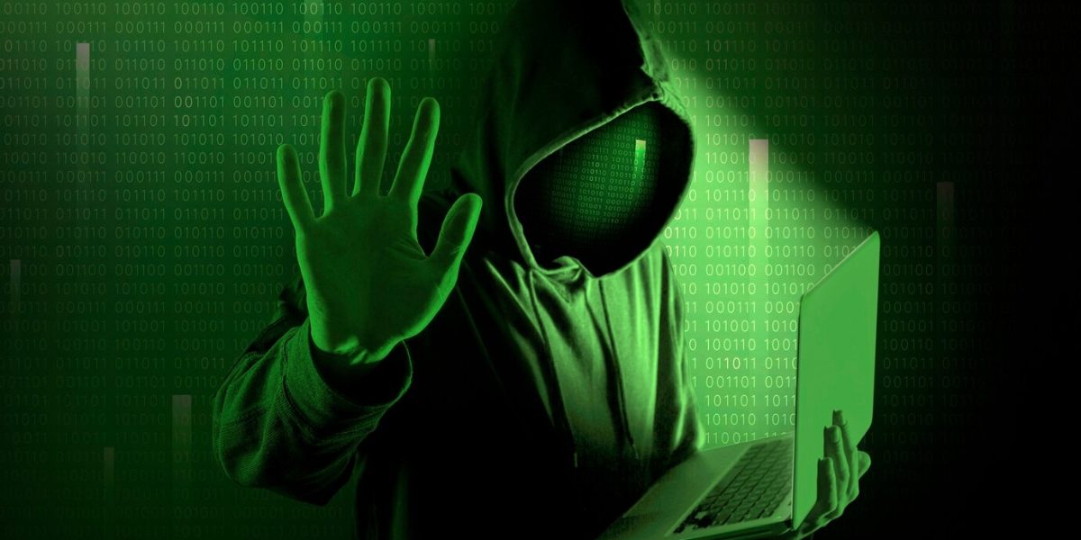 Green hued cybercriminal using laptop to deploy worm malware.